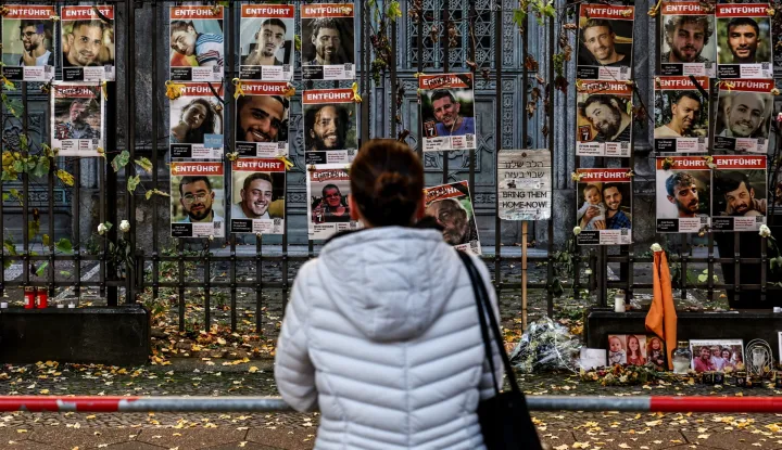 epa12451253 A pedestrian looks on at portraits of Israeli hostages and victims displayed on a fence in front of the New Synagogue in Berlin, Germany, 13 October 2025. The first phase of the Gaza peace agreement, reached between Israel and Hamas, includes the release of Israeli hostages and Palestinian prisoners, a partial withdrawal of Israeli forces, and the delivery of humanitarian aid to Gaza. EPA/FILIP SINGER