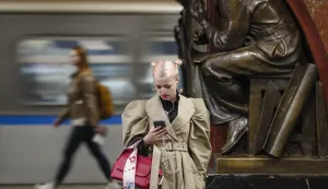 epaselect epa10580283 A woman looks at her phone while waiting for a train at a metro station in Moscow, Russia, 19 April 2023. EPA/YURI KOCHETKOV