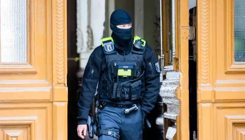 24 May 2023, Deutschland, Berlin: Ein Polizist steht bei einer Hausdurchsuchung in Berlin-Kreuzberg in einem Hauseingang. Polizei und Staatsanwaltschaft haben im Zuge eines Ermittlungsverfahrens zu Mitgliedern der Letzten Generation 15 Objekte in sieben Bundesländern durchsucht. Photo: Christoph Soeder/dpa Photo: Christoph Soeder/DPA