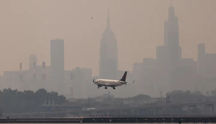 epa10680359 An airplane lands at LaGuardia airport with buildings in Manhattan skyline in the background as smoke from wildfires burning in Canada continues to create unhealthy air quality conditions in New York, New York, USA, 08 June 2023. New York City continues to be under an air quality alert as result of the smoke, which is affecting large portions of the United States and causing flight delays around as well as ground stops due to poor visibility. EPA/JUSTIN LANE