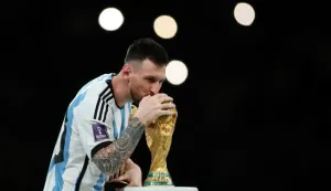 epa10372941 Lionel Messi of Argentina kisses the World Cup trophy as he passes it with his trophy for the best player of the FIFA World Cup 2022 Final between Argentina and France at Lusail stadium, Lusail, Qatar, 18 December 2022. EPA/Tolga Bozoglu