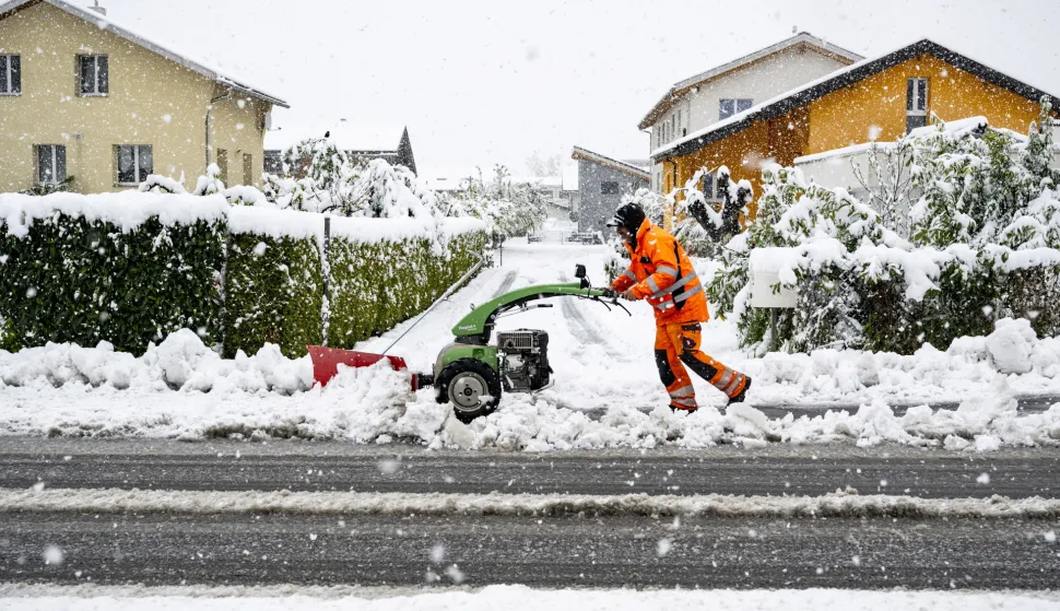 epa12036356 A municipal employee removes snow from a road with a machine in Saillon, Canton Valais, Switzerland, 17 April 2025. Storms brought flooding, landslides, heavy snow, and fallen trees to Valais, severely disrupting traffic. Numerous rail and road links were closed, with the Brig region hit particularly hard. EPA/JEAN-CHRISTOPHE BOTT