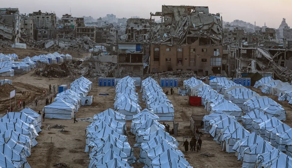 epa12533945 Displaced Palestinians walk amid makeshift shelters erected beside the ruins of destroyed buildings in northern Gaza City, Gaza Strip, 18 November 2025, amid a ceasefire between Israel and Hamas. Around 1.9 million people in Gaza, nearly 90 percent of the population, have been displaced since the Israel-Hamas conflict began in October 2023, according to the UN. EPA/MOHAMMED SABER