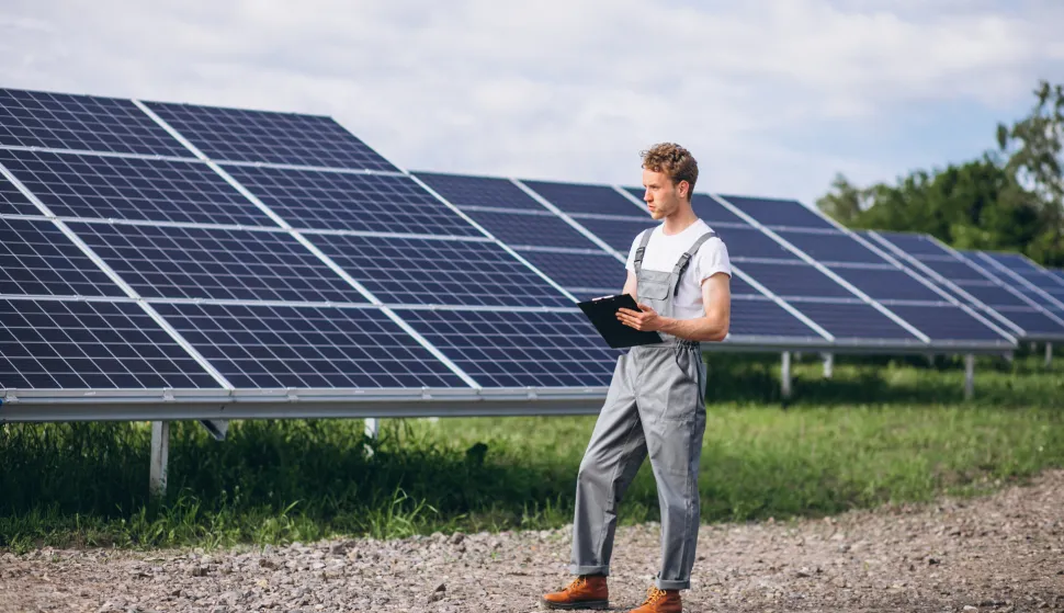 Man worker in the firld by the solar panels