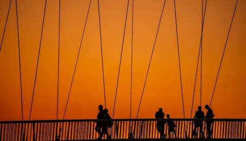 15.08.2025., Osijek, Prekrasan zalazak sunca na Dravi u Osijeku i siluete setaca na ojesackom mostu Photo: Emica Elvedji/PIXSELL