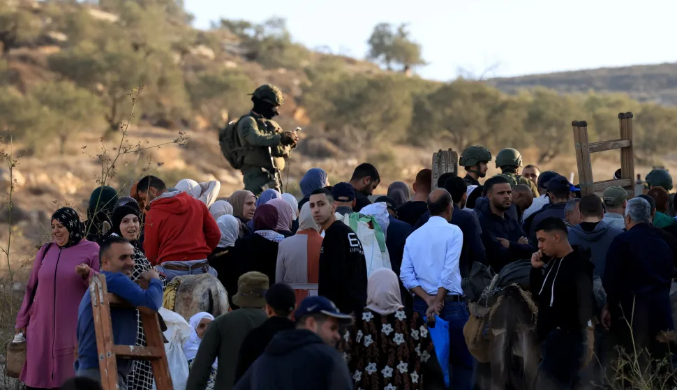 epa12541406 Israeli soldiers on guard as Palestinian farmers make their way to pass a gate giving them access to their olive feild close to the Alon More settelment near the West Bank village of Salem, near the West Bank city of Nablus, 22 November 2025. Farmers across the West Bank have faced repeated attacks by Israeli settlers and soldiers during the olive harvest season, in assaults often including physical violence, harassment, uprooting of trees, and blocking access to agricultural lands located near or within settlement areas. EPA/ALAA BADARNEH