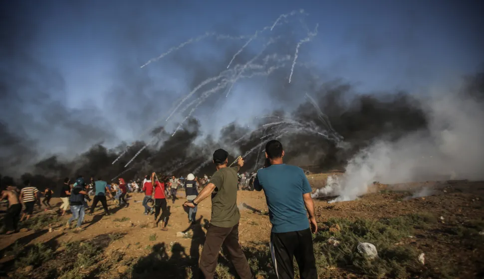 epa06914465 Palestinians protesters run for cover from Israeli tear-gas during the clashes with Israeli troops near the border with Israel in eastern Gaza Strip, 27 July 2018. A fourteen years old boy and other protester were killed during the clashes after Friday protests near the border with Israel in the eastern Gaza Strip. EPA/HAITHAM IMAD