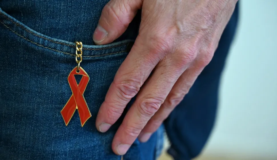PRODUCTION - 27 November 2025, Berlin: A red ribbon, the international symbol of solidarity with people living with HIV and commitment to AIDS prevention, hangs from the trousers of a man at the Berliner Aids-Hilfe e.V.. World Aids Day takes place every year on December 1. Photo: Elisa Schu/dpa Photo: Elisa Schu/DPA