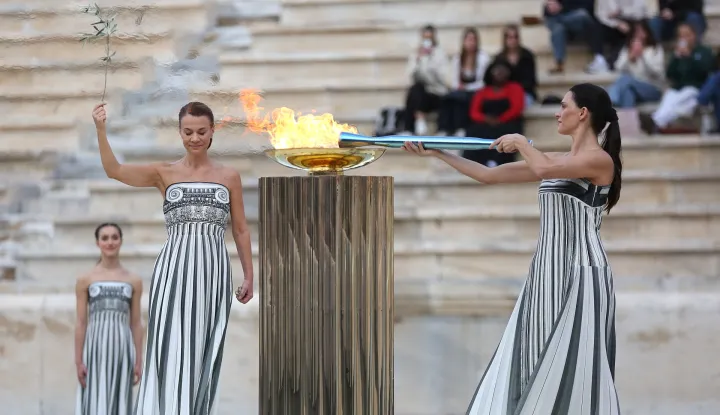 epa12569068 Greek actress Mary Mina, playing the role of the High Priestess, lights the Olympic Torch during the handover ceremony of the Olympic Flame for the Milano Cortina 2026 Winter Olympics, at the Panathenaic Stadium in Athens, Greece, 04 December 2025. EPA/ORESTIS PANAGIOTOU