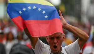 A supporter of Venezuelan President Nicolas Maduro holds a Venezuelan flag during a march to Miraflores Palace for a ceremony swearing in new community organisations, amid rising tensions between the Trump administration and the government of Maduro, in Caracas, Venezuela, December 1, 2025. REUTERS/Fausto Torrealba Photo: FAUSTO TORREALBA/REUTERS