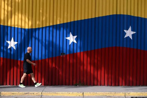 A man walks past a mural with the colors of the Venezuelan flag, after U.S. President Donald Trump said on Saturday that the airspace above and around Venezuela would be completely closed, amid rising tensions between the Trump administration and the government of Venezuelan President Nicolas Maduro, in Caracas, Venezuela, November 29, 2025. REUTERS/Gaby Oraa Photo: GABY ORAA/REUTERS