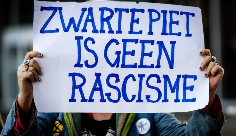 epa07078466 A sympathizer of the traditional figure Black Pete display a placard reading, 'Zwarte Piet is not racism', outside the court in Leeuwarden, Netherlands, 08 October 2018. Some 34 people suspected of blocking a road on the day of the national Sinterklaas race in 2017, had to appear in court. Black Pete or Zwarte Piet is the companion of Saint Nicolas during the Sinterklaas (Saint Nicolas) festival celebrated on the evening of 05 December, and has become the subject of much controversy in recent years as some people think it is racist. EPA/ROBIN OF LONKHUIJSEN