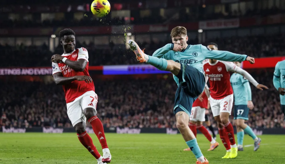 epa12590606 Bukayo Saka of Arsenal (L) in action against David Moller Wolfe of Wolverhampton during the English Premier League match between Arsenal FC and Wolverhampton Wanderers, in London, Britain, 13 December 2025. EPA/TOLGA AKMEN EDITORIAL USE ONLY. No use with unauthorized audio, video, data, fixture lists, club/league logos, 'live' services or NFTs. Online in-match use limited to 120 images, no video emulation. No use in betting, games or single club/league/player publications.