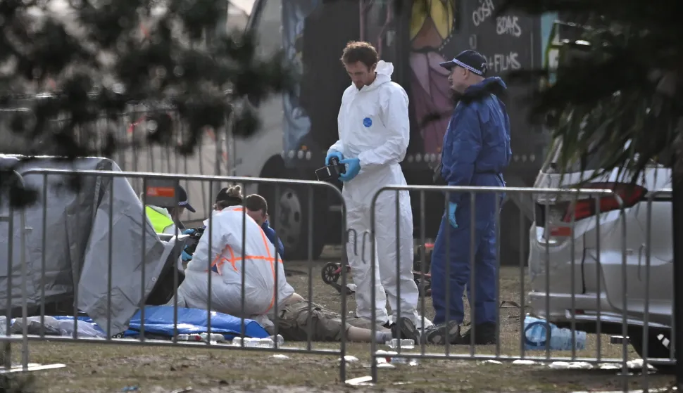 epa12592729 Forensic officers examine a victim's body at the scene of a shooting at Bondi Beach in Sydney, Australia, 15 December 2025. At least 16 people were killed in a shooting incident on 14 December during the Jewish community's Hanukkah festival celebrations at Bondi Beach in Sydney. EPA/DEAN LEWINS AUSTRALIA AND NEW ZEALAND OUT