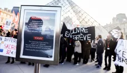 epa12593800 A message announces a delay in the museum's opening on the first day of a strike by Louvre workers in front of the museum's pyramid in Paris, France, 15 December 2025. Some 400 Louvre workers began striking today, demanding better working conditions and improvements to the museum's facilities. EPA/Teresa Suarez