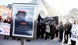 epa12593800 A message announces a delay in the museum's opening on the first day of a strike by Louvre workers in front of the museum's pyramid in Paris, France, 15 December 2025. Some 400 Louvre workers began striking today, demanding better working conditions and improvements to the museum's facilities. EPA/Teresa Suarez