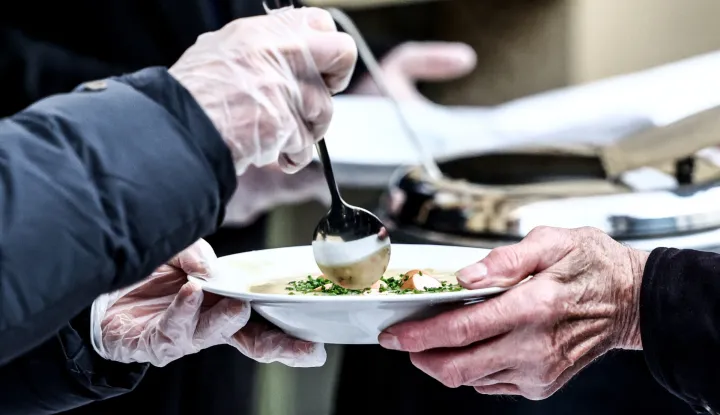 epa12600807 A person in need receives warm food as German President Frank-Walter Steinmeier and his wife Elke Buedenbender distribute food to people in need, in front of Strassenfeger's cafe in Berlin, Germany, 18 December 2025. EPA/FILIP SINGER