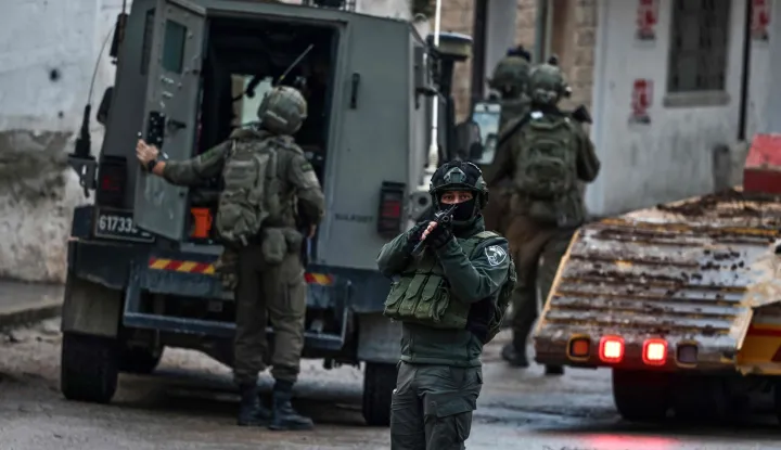 Israeli security forces secure a street as they leave the Palestinian village of Bizariya, in the occupied West Bank, where Israeli authorities demolished the house of a Palestinian man killed in July after he and another man reportedly killed an Israeli settler on the same day, on December 24, 2025. (Photo by Zain JAAFAR/AFP)