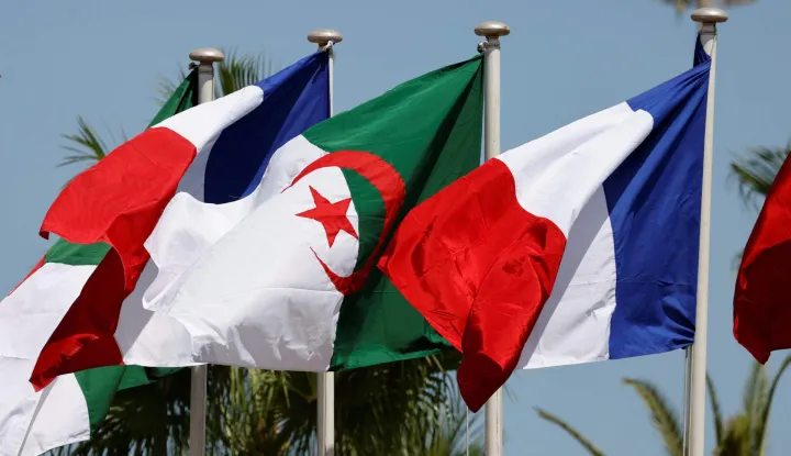 (FILES) This picture taken on August 25, 2022 shows French and Algerian flags ahead of the arrival of the French president in Algiers for an official visit. Algeria's adoption of a law criminalising French colonisation (1830?1962) is "a clearly hostile initiative, both to efforts to resume Franco-Algerian dialogue and to a calm approach to addressing issues of memory," France's Foreign Ministry says on December 24, 2025. (Photo by Ludovic MARIN/AFP)