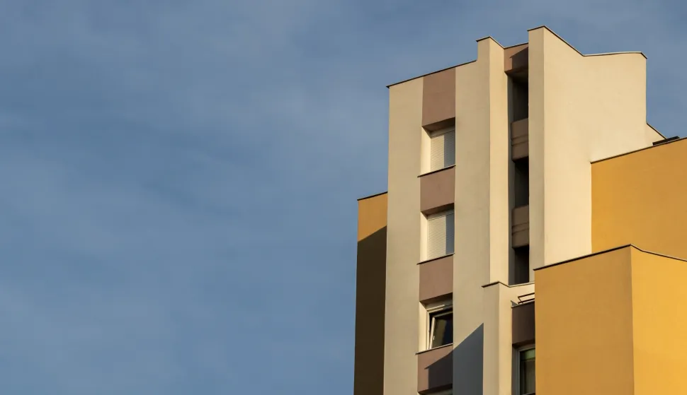 A vertical low angle shot of a concrete white and brown modern building under the cloudy skyzgrada stanovi stanogradnja ilustracija freepik