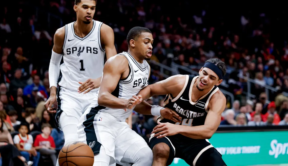 epa12604185 Atlanta Hawks forward Asa Newell (R) in action against San Antonio Spurs forward Keldon Johnson (C) and San Antonio Spurs forward Victor Wembanyama (L) during the first half of an NBA basketball game between the San Antonio Spurs and the Atlanta Hawks in Atlanta, Georgia, USA, 19 December 2025. EPA/ERIK S. LESSER SHUTTERSTOCK OUT