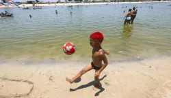 epa12613212 A child plays with a ball at the beach of the artificial lake Piscinao de Ramos in Rio de Janeiro, Brazil, 26 December 2025. The Brazilian National Institute of Meteorology issued a red alert on Friday for the entire territory of the states of Sao Paulo and Rio de Janeiro due to a heatwave that is expected to last until Monday. EPA/Antonio Lacerda