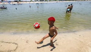 epa12613212 A child plays with a ball at the beach of the artificial lake Piscinao de Ramos in Rio de Janeiro, Brazil, 26 December 2025. The Brazilian National Institute of Meteorology issued a red alert on Friday for the entire territory of the states of Sao Paulo and Rio de Janeiro due to a heatwave that is expected to last until Monday. EPA/Antonio Lacerda