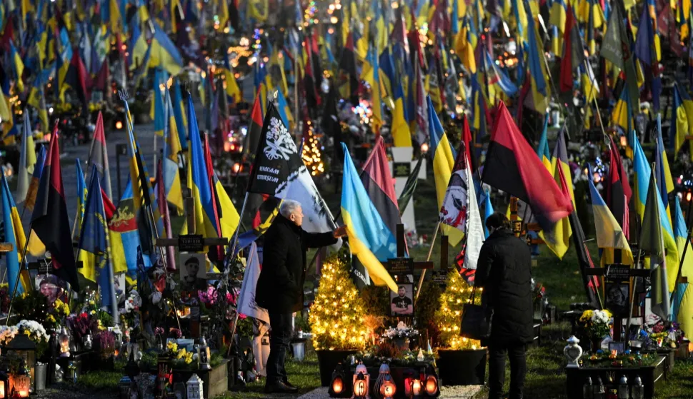 People visit the graves of fallen Ukrainian soldiers decorated with Christmas trees and New Year's decorations at the Lychakiv Military Cemetery, on the day before Christmas Eve, in Lviv on December 23, 2025, amid the Russian invasion of Ukraine. (Photo by YURIY DYACHYSHYN/AFP)