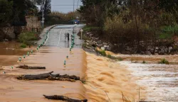 Pedestrians walk next to a flooded road due to the overflowing of the Agly river at the entrance of Rivesaltes in the Pyrenees-Orientales department in south-western France on December 26, 2025. Aude, Pyr?n?es-Orientales and Haute-Corse have been placed on orange alert for rain?flooding or floods by M?t?o-France until midnight on December 26, 2025. (Photo by Jean-Christophe MILHET/AFP)