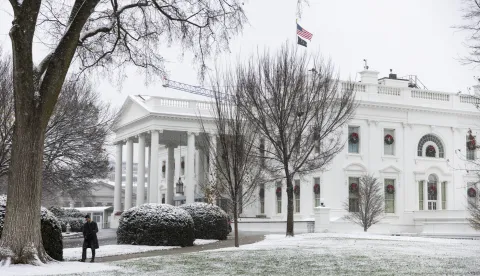 epa12572462 A person walks as a light snow falls on the White House in Washington, DC, USA, 05 December 2025. The capital city's first snow of the season is not expected to accumulate more than one inch. EPA/JIM LO SCALZO