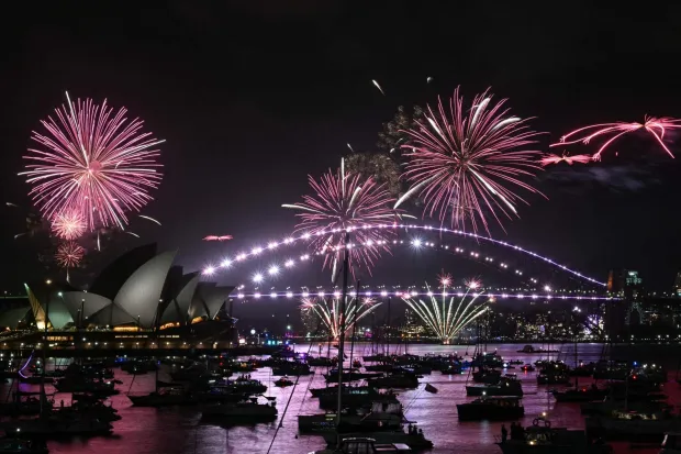 The "family fireworks" light up the Opera House and the Sydney Harbour Bridge three hours ahead of the main show at midnight in Sydney on New Year's Eve on December 31, 2025. (Photo by Saeed KHAN/AFP)