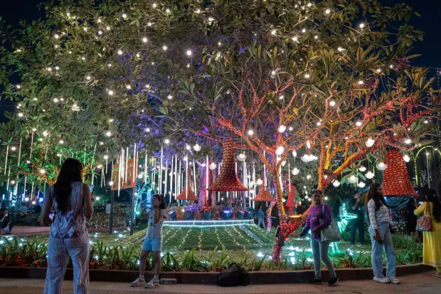 Revellers pose for photographs at an illuminated sea promenade during New Year's Eve in Mumbai on December 31, 2025. (Photo by Punit PARANJPE/AFP)