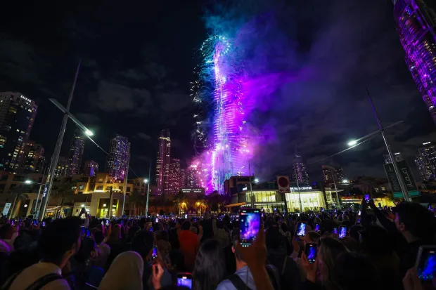 People watch fireworks light up the sky around the Burj Khalifa during New Year celebrations in Dubai, early on January 1, 2026. (Photo by Fadel SENNA/AFP)