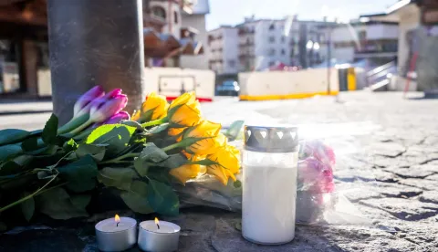 A photograph taken on January 1, 2026 shows flowers and candles laid on the ground near the bar Le Constellation following a fire that ripped through the venue in Crans-Montana, during New Year's Eve celebrations. Several dozen people are presumed dead and around 100 injured after a fire ripped through a crowded bar in the luxury Swiss ski resort town of Crans-Montana, police said early January 1, 2026. (Photo by MAXIME SCHMID/AFP)
