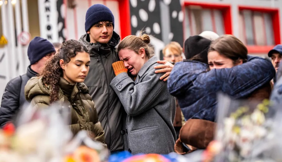 TOPSHOT - Mourners gather near the bar Le Constellation where a fire ripped through the venue during New Year's celebrations in the Alpine ski resort town of Crans-Montana killing around 40 people and injuring more than 100 others, in Crans-Montana on January 2, 2026. Investigators raced on January 2, 2026 to identify the victims of a fire that ripped through a bar in the Swiss Alps town of Crans-Montana, turning a New Year's celebration into one of the country's worst tragedies. Frederic Gisler, police commander in the Wallis canton in southwestern Switzerland, told reporters that authorities had counted "around 40 people who have died and around 115 injured, most of them seriously". (Photo by MAXIME SCHMID/AFP)
