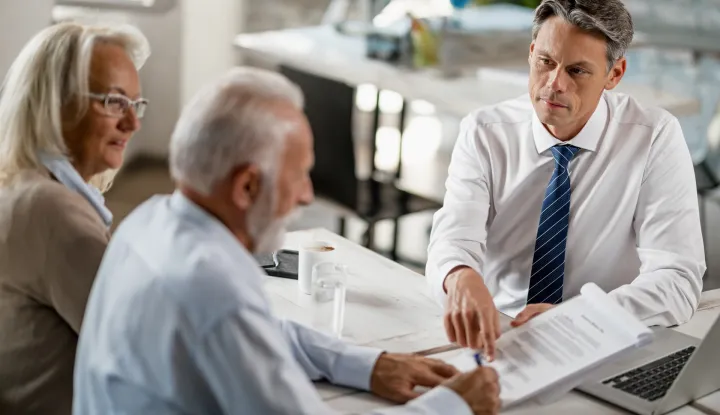 Bank manager having a meeting with senior couple and pointing at place they need to sign on the contract.banka novac osiguranje ilustracija stariji par umirovljenik umirovljenici freepik