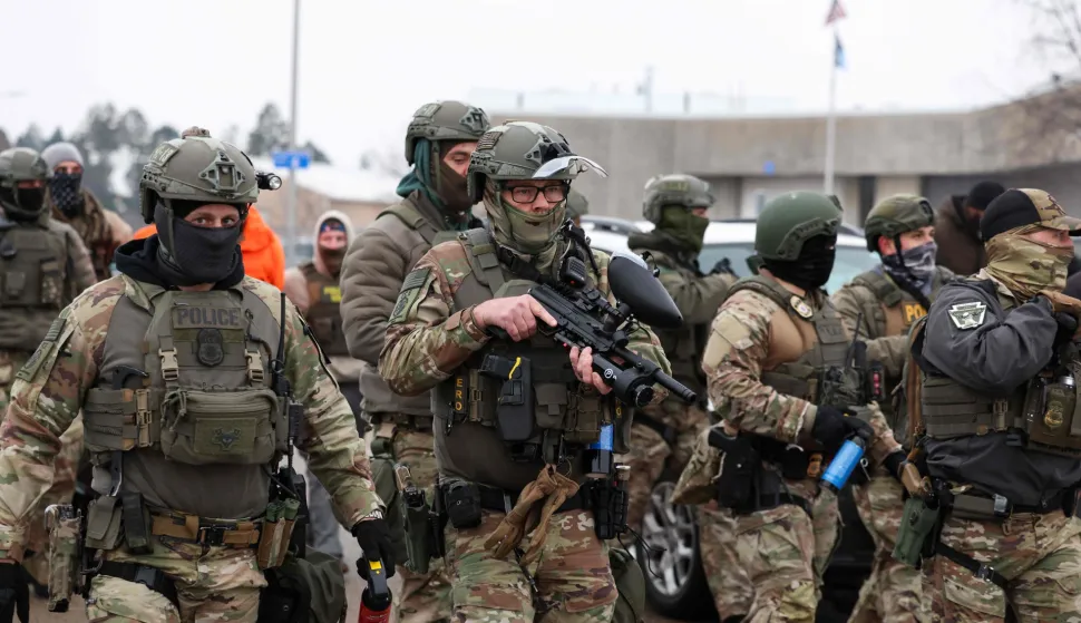 US Border Patrol agents holding less-lethal weapons stand guard at the Bishop Henry Whipple Federal Building in Minneapolis, Minnesota, on January 8, 2026. A US Immigration and Customs Enforcement (ICE) agent shot and killed an American woman on the streets of Minneapolis January 7, leading to huge protests and outrage from local leaders who rejected White House claims she was a domestic terrorist. The woman, identified in local media as 37-year-old Renee Nicole Good, was hit at point blank range as she apparently tried to drive away from agents who were crowding around her car, which they said was blocking their way. (Photo by CHARLY TRIBALLEAU/AFP)