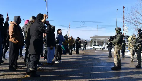 Federal law enforcement agents face protesters outside the Bishop Henry Whipple Federal Building during a demonstration over the fatal shooting of Renee Good by a US Immigration and Customs Enforcement (ICE) agent, in Minneapolis, Minnesota, on January 9, 2026. A US Immigration and Customs Enforcement (ICE) agent shot and killed an American woman on the streets of Minneapolis January 7, leading to huge protests and outrage from local leaders who rejected White House claims she was a domestic terrorist. The woman, identified in local media as 37-year-old Renee Nicole Good, was hit at point blank range as she apparently tried to drive away from agents who were crowding around her car, which they said was blocking their way. (Photo by Octavio JONES/AFP)
