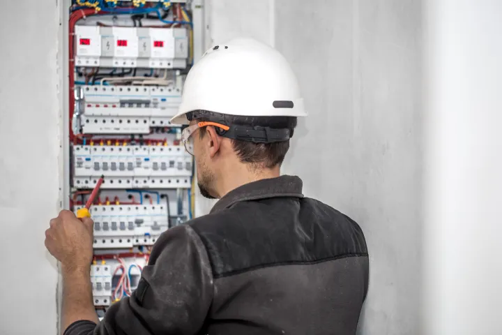 Man, an electrical technician working in a switchboard with fuses. Installation and connection of electrical equipment. Professional with tools in hand. concept of complex work, space for text.struja električna energija, električarfreepik