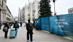 People walk past Milano Cortina 2026 Winter Olympic Games banners in Duomo's square in Milan on Januray 9, 2026. (Photo by Stefano RELLANDINI/AFP)