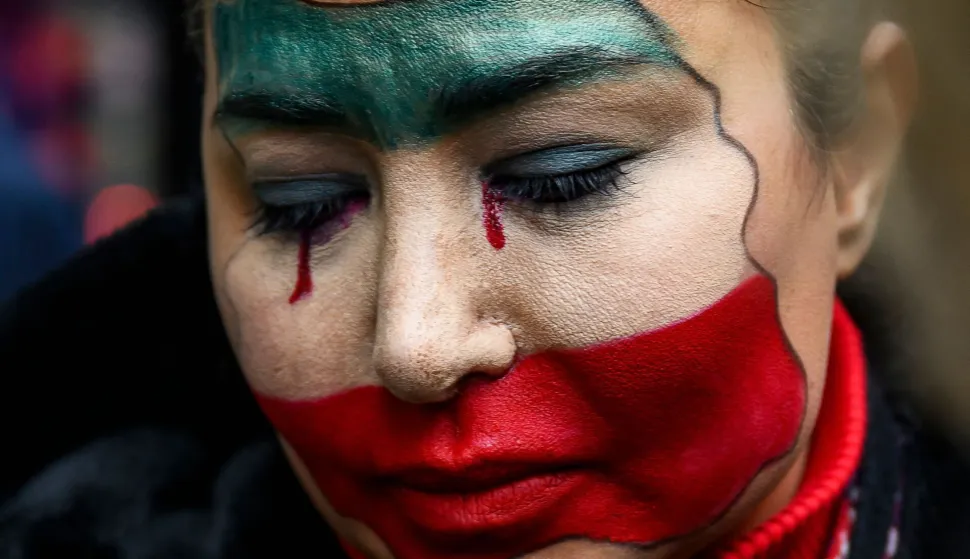 An anti-Iranian regime protester with her face painted in the colours of the Iranian flag takes part in a demonstration outside the Iranian Consulate, in Istanbul, on January 11, 2026. At least 192 protesters have been killed in Iran's biggest movement against the Islamic republic in more than three years, a rights group said on January 11, 2026 as warnings grew that authorities were committing a "massacre" to quell the demonstrations (Photo by Yasin AKGUL/AFP)