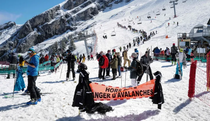 (FILES) Skiers queue for the lift near a sign warning of avalanche risk during the re-opening of the ski resort at Col de la Balme in La Clusaz, French Alps on May 23, 2021 as the country loosened Covid-19 restrictions. Two avalanches killed two skiers in the French Alps on January 11, 2026, resort officials said, following the deaths of three off-piste skiers a day earlier in similar incidents. In one incident, a British skier aged about 50 was buried while skiing off-trail, according to a statement released by La Plagne ski resort in southeastern France. (Photo by Olivier CHASSIGNOLE/AFP)