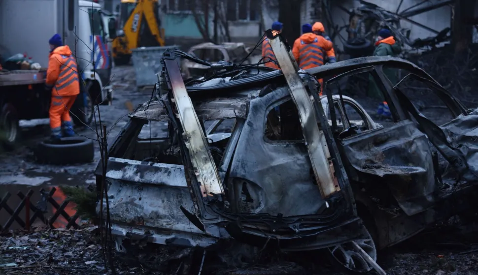 Communal workers clean debris in the courtyard of a damaged residential building next to destroyed cars following a drone attack in Dnipro on January 7, 2026, amid the Russian invasion in Ukraine. (Photo by Mykola SYNELNYKOV/AFP)