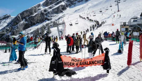 (FILES) Skiers queue for the lift near a sign warning of avalanche risk during the re-opening of the ski resort at Col de la Balme in La Clusaz, French Alps on May 23, 2021 as the country loosened Covid-19 restrictions. Two avalanches killed two skiers in the French Alps on January 11, 2026, resort officials said, following the deaths of three off-piste skiers a day earlier in similar incidents. In one incident, a British skier aged about 50 was buried while skiing off-trail, according to a statement released by La Plagne ski resort in southeastern France. (Photo by Olivier CHASSIGNOLE/AFP)