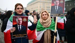 13 January 2026, Berlin: "Pahlavi will come back" is written on a sign with the image of Reza Pahlavi, son of the last Shah of Iran, during a demonstration in support of the nationwide mass protests against the government in Iran on Paris Square. Photo: Sebastian Christoph Gollnow/dpa Photo: Sebastian Christoph Gollnow/DPA