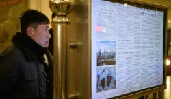 (FILES) A man reads North Korea's Rodong Sinmun newspaper, which includes an article (centre, 2nd from bottom) on the inauguration of US President Donald Trump, on a digital monitor displayed in the Kaeson Station of the Pyongyang Metro in Pyongyang on January 22, 2025. South Korea said on December 26 it will reclassify North Korea's long-banned state newspaper as general information, easing public access, in the latest overture from the administration of dovish President Lee Jae Myung. Seoul's government convened on December 26 an inter-agency meeting and confirmed a consensus among the relevant parties regarding the "reclassification of the Rodong Sinmun newspaper from special material to general material", it said in a statement. (Photo by KIM Won Jin/AFP)