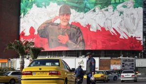 Iranians ride their motorbike past a huge banner of former Iran Islamic Revolutionary Guard Corps (IRGC) Quds Force commander Qasem Soleimani ahead of the sixth anniversary of his assassination Iraq, at Valiasr Square in Tehran, on December 31, 2025. Soleimani was killed on January 3, 2020, in a targeted US airstrike at Baghdad airport in Iraq. (Photo by ATTA KENARE/AFP)