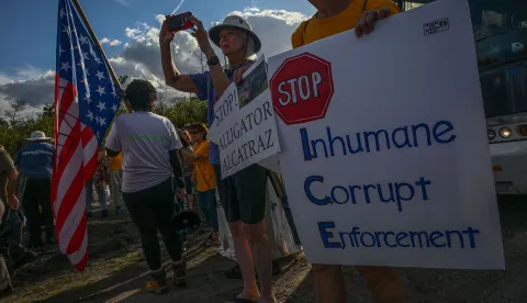Demonstrators protest against Immigration and Customs Enforcement (ICE) and demanding the closure of the immigrant detention center known as "Alligator Alcatraz" outside the center at the Dade-Collier Training and Transition Airport in Ochopee, Florida, on January 11, 2026. A US Immigration and Customs Enforcement (ICE) agent shot and killed 37-year-old Renee Nicole Good on the streets of Minneapolis on January 7, leading to huge protests and outrage from local leaders who rejected White House claims she was a domestic terrorist. (Photo by Giorgio VIERA/AFP)