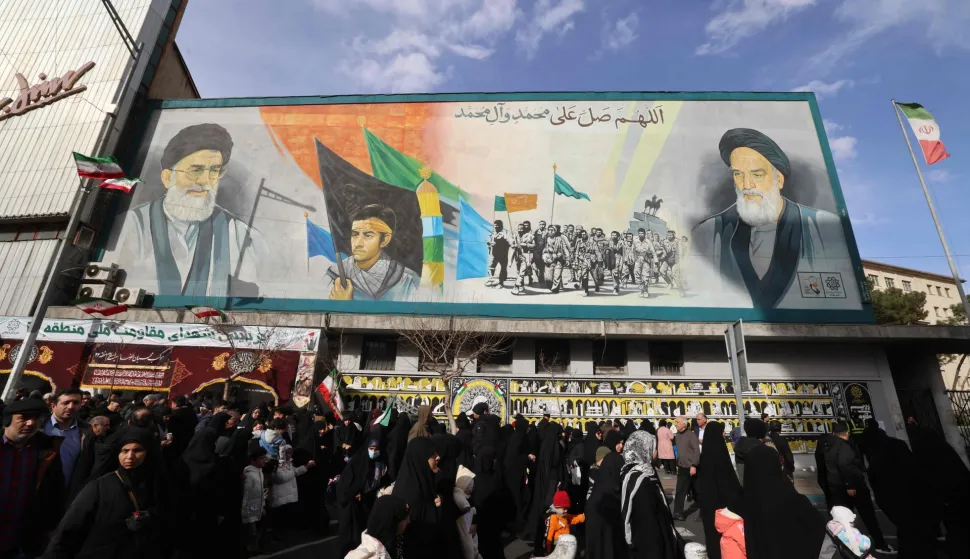 People walk past a banner depicting Iran?s Supreme Leader Ayatollah Ali Khamenei and late leader Ruhollah Khomeini on Enghelab (Revolution) Square in Terhan on January 14, 2026. Iran on Januray 14 vowed fast-track trials for people arrested over a massive wave of protests, after US President Donald Trump threatened "very strong action" if the Islamic republic goes ahead with hangings. In Tehran, authorities held a funeral ceremony for over 100 members of the security forces and other "martyrs" killed in the demonstrations, which authorities have branded as "riots" while accusing protesters of waging "acts of terror". (Photo by ATTA KENARE/AFP)