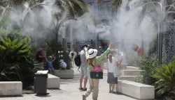 epa12204409 Tourists cool off under a cloud of mist at the Plaza de la Reina during a heat wave in Valencia, Spain, 29 June 2025. Spain is undergoing its first summer heat wave due to a broad anticyclone originating from the interior of the African continent which is expected to last until 01 July, according to the State Meteorological Agency (AEMET). EPA/MANUEL BRUQUE